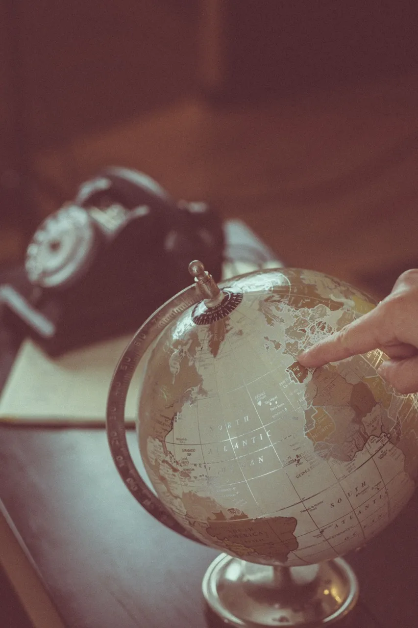 Un doigt pointé sur un globe terrestre ancien, à l'agence